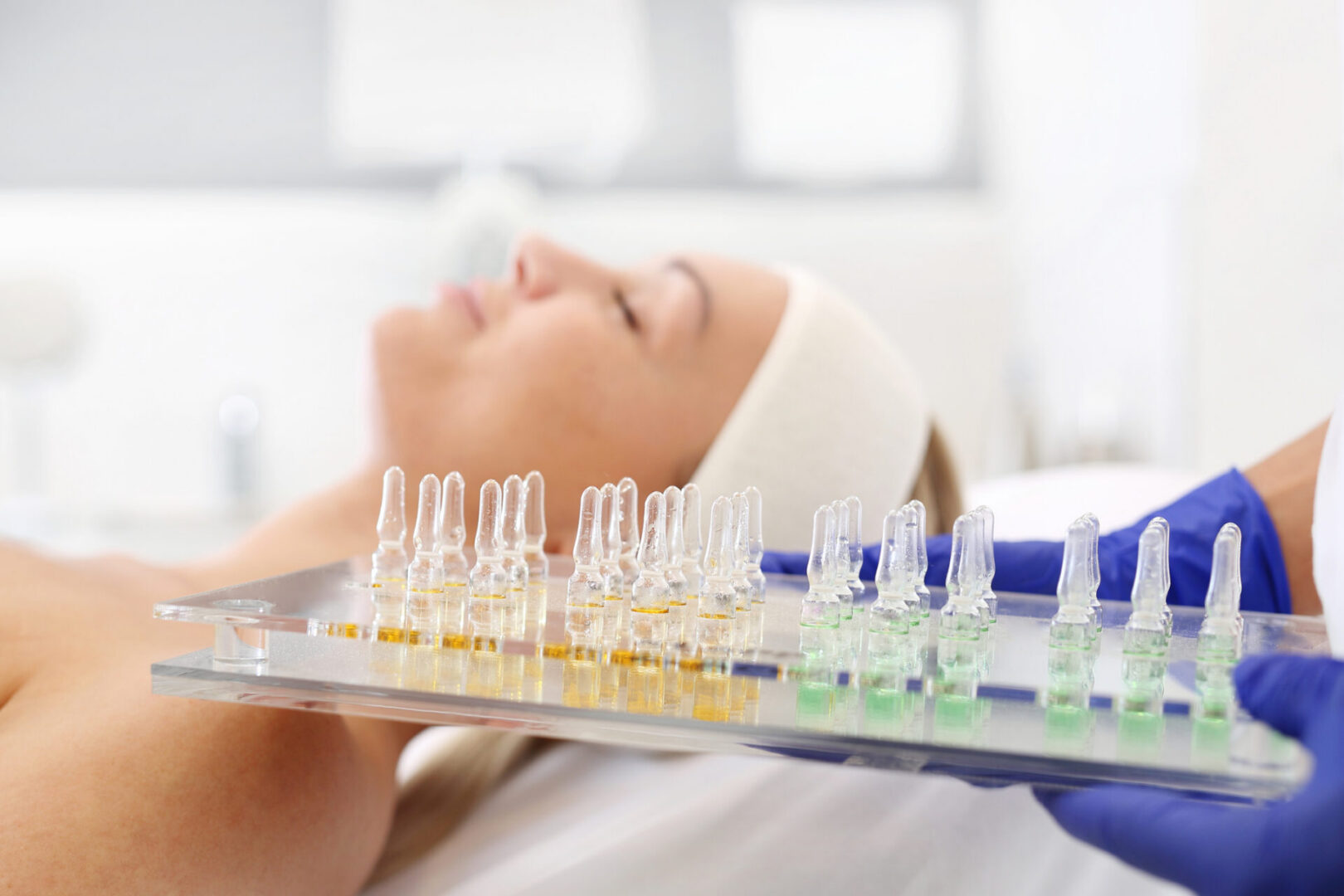 The beautician holds trays with cosmetic preparations in her hand.