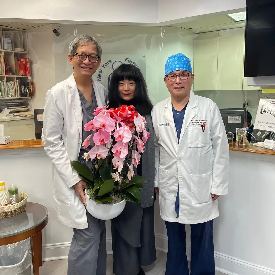 Three people holding a potted plant