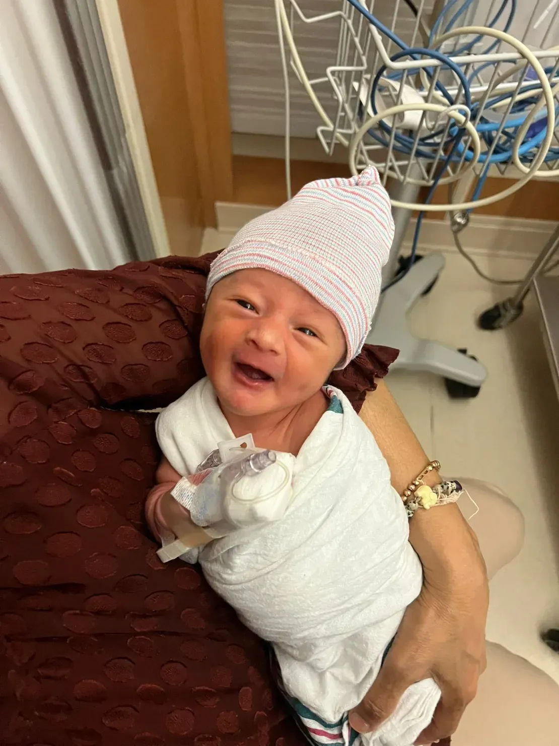 Baby wrapped in white blanket, smiling