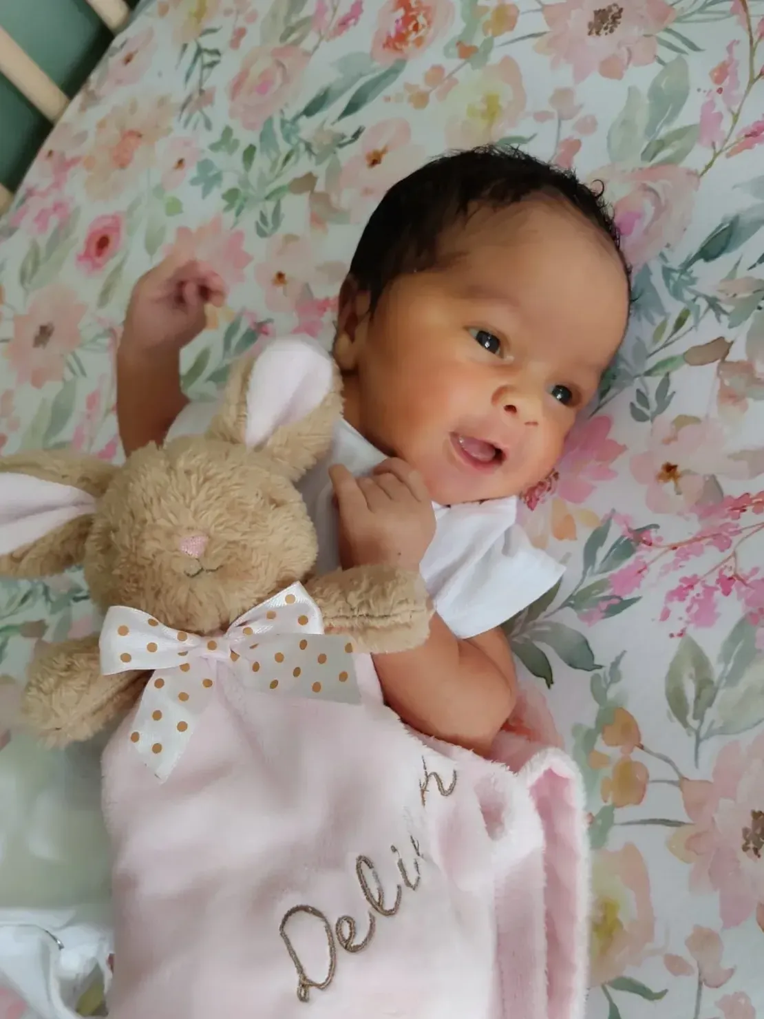 Baby with plush bunny on floral blanket