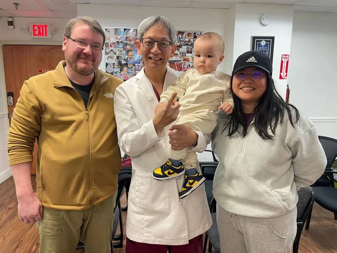 Group smiling with baby in casual setting.