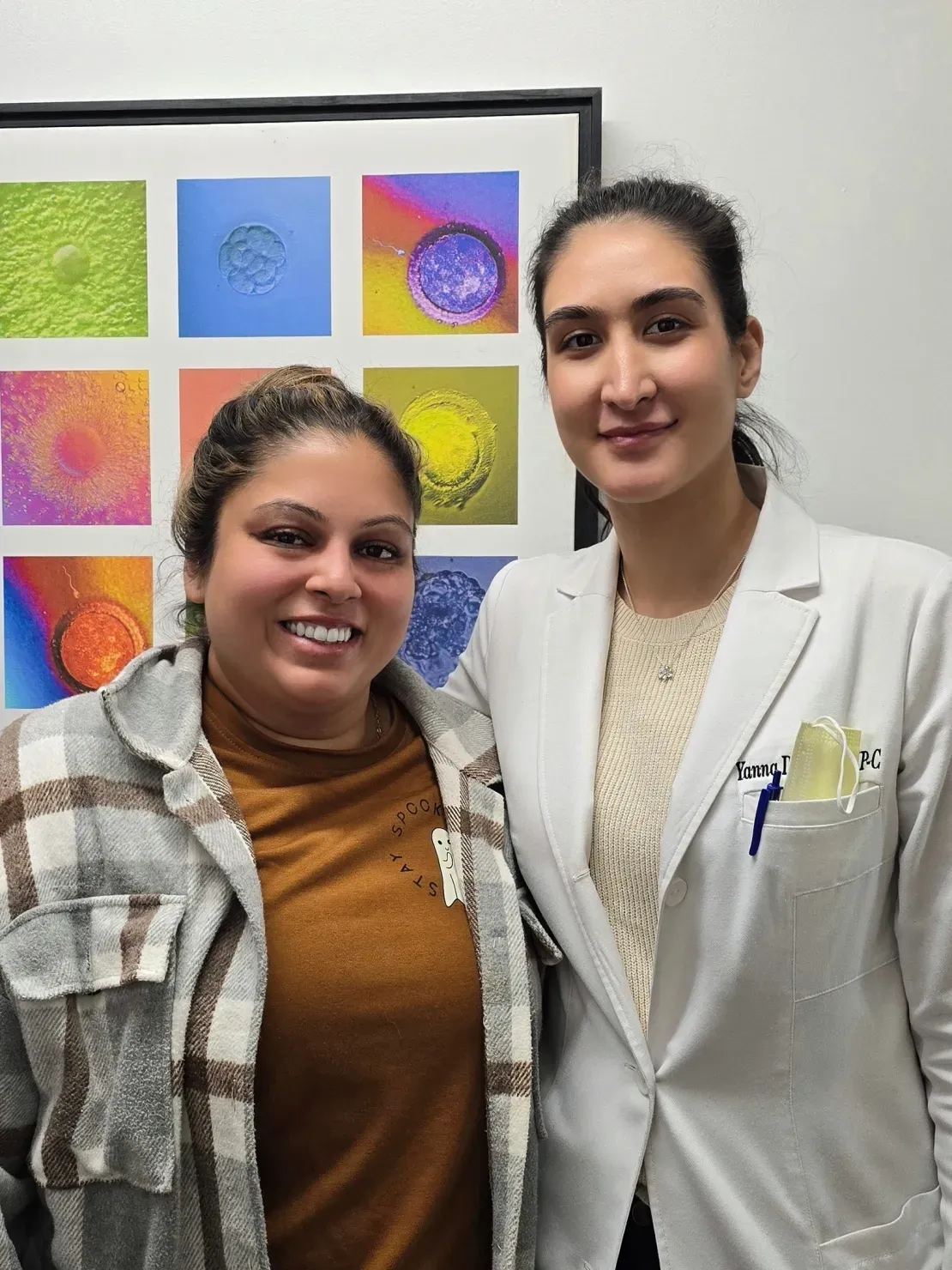 Two women smiling in front of artwork