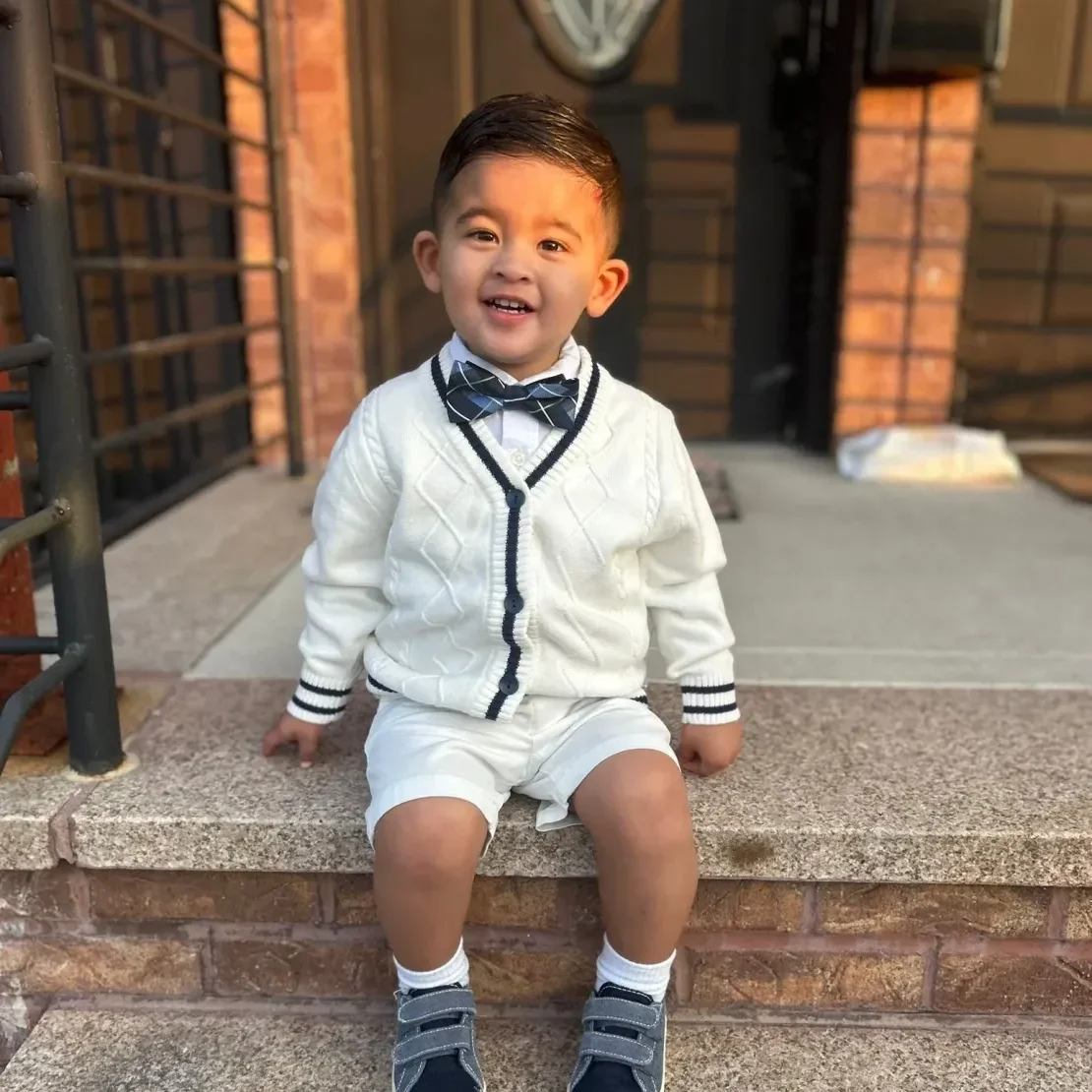 Smiling toddler in bow tie outside house